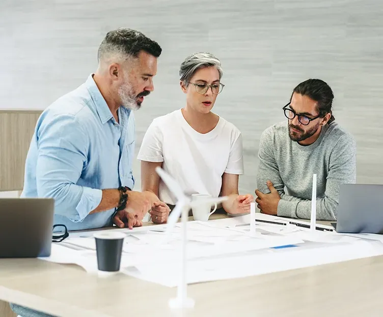 Image of three energy professionals discussing wind turbine renewable energy project. Owner's engineering.