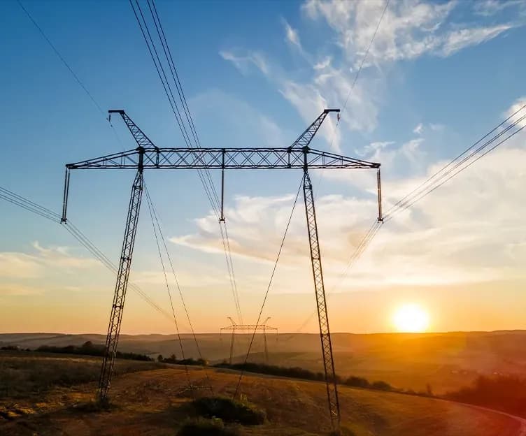 Image of transmission lines on mountains at sunset. Grid analysis and interconnection. Transmission and distribution capacity studies.